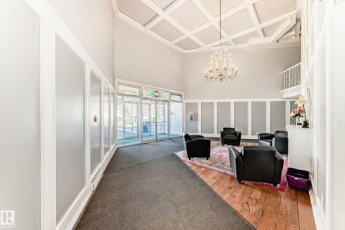 Spacious entryway featuring a coffered ceiling, elegant chandelier, and a wood-finish flooring section - 423 5125 Riverbend Road, Edmonton, AB - Indoor Photo Showing Other Room