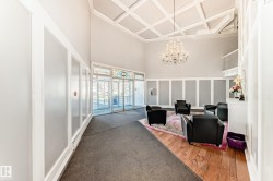 Spacious entryway featuring a coffered ceiling, elegant chandelier, and a wood-finish flooring section - 