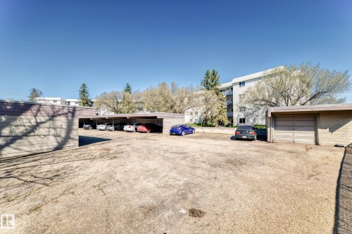 Surface parking area featuring covered stalls and individual garage units - 423 5125 Riverbend Road, Edmonton, AB - Outdoor