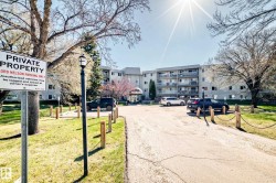 Multi-story building featuring individual balconies, a covered main entrance, and an asphalt parking area with chain-post barriers - 