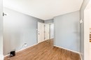 Interior space featuring wood-finish flooring, light grey painted walls, white trim, and a textured white ceiling - 423 5125 Riverbend Road, Edmonton, AB  - Indoor Photo Showing Other Room 