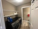Dedicated laundry area featuring modern appliances, wall-mounted wire shelving, and wood-finish flooring - 871 Ebbers Crescent, Edmonton, AB  - Indoor Photo Showing Laundry Room 