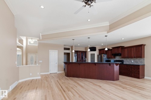 Spacious interior featuring light wood-finish flooring, a kitchen island with pendant lighting, dark wood cabinetry, and recessed ceiling lights - 30 Valleyview Ridge, Fort Saskatchewan, AB - Indoor Photo Showing Kitchen