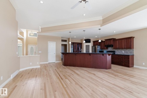 Spacious open-concept living area featuring light wood-finish flooring, a vaulted ceiling with recessed lighting and a ceiling fan, and a kitchen island with pendant lighting - 30 Valleyview Ridge, Fort Saskatchewan, AB - Indoor Photo Showing Kitchen