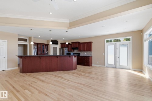 Open-concept living area featuring blonde wood-finish flooring, a kitchen island with dark cabinetry, recessed lighting, double French doors, and a ceiling fan - 30 Valleyview Ridge, Fort Saskatchewan, AB - Indoor Photo Showing Kitchen