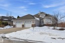 Single-family residence featuring a double-car garage, stone veneer accents, an arched entry door, a bay window, and a dormer - 30 Valleyview Ridge, Fort Saskatchewan, AB  - Outdoor With Facade 