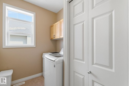 Utility area featuring wood-finish cabinetry, a single window, and neutral wall tones - 30 Valleyview Ridge, Fort Saskatchewan, AB - Indoor Photo Showing Laundry Room