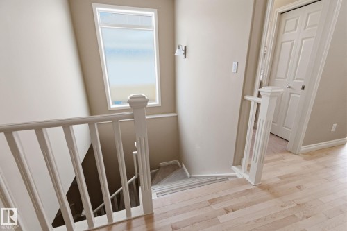 Upper landing featuring light wood-finish flooring, white spindle railings, and a window with frosted lower pane - 30 Valleyview Ridge, Fort Saskatchewan, AB - Indoor Photo Showing Other Room