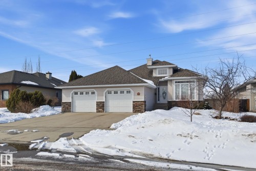 Two-car garage with white paneled doors, stone accents, and light-colored siding - 30 Valleyview Ridge, Fort Saskatchewan, AB - Outdoor With Facade