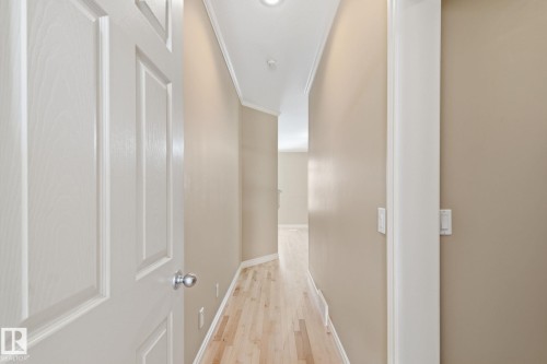 Hallway featuring light wood-finish flooring, neutral wall paint, white baseboards, and crown molding - 30 Valleyview Ridge, Fort Saskatchewan, AB - Indoor Photo Showing Other Room