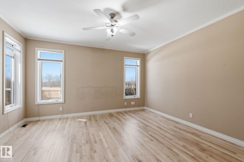 Spacious room featuring light wood-finish flooring, neutral wall tones, and white crown molding - 30 Valleyview Ridge, Fort Saskatchewan, AB - Indoor Photo Showing Other Room