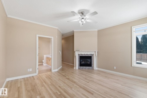 Living space featuring light wood-finish flooring, a white ceiling fan with integrated lighting, and a corner fireplace with an ornate white mantel and dark tile surround - 30 Valleyview Ridge, Fort Saskatchewan, AB - Indoor With Fireplace