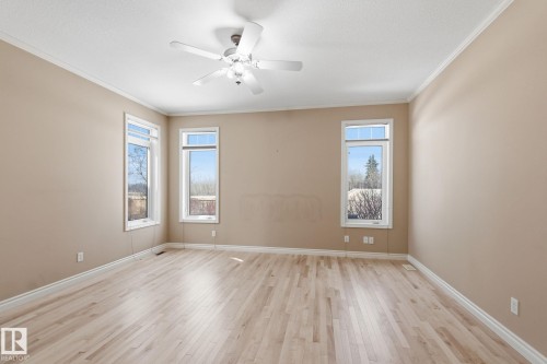 Spacious room featuring light wood-finish flooring, neutral wall tones, crown molding, and a ceiling fan with integrated lighting - 30 Valleyview Ridge, Fort Saskatchewan, AB - Indoor Photo Showing Other Room