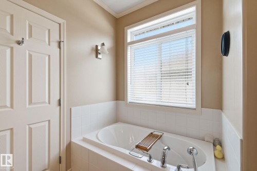 Soaking tub with white tile surround, chrome fixtures, and a large window featuring horizontal blinds - 30 Valleyview Ridge, Fort Saskatchewan, AB - Indoor Photo Showing Bathroom