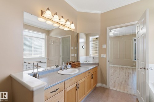 Double vanity with wood-finish cabinetry, a single basin sink, and a large mirror with integrated lighting - 30 Valleyview Ridge, Fort Saskatchewan, AB - Indoor Photo Showing Bathroom