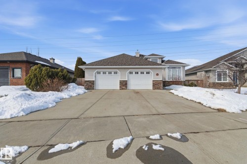 Split-level residence featuring a two-car garage with panel doors, stone veneer accents, and bay windows - 30 Valleyview Ridge, Fort Saskatchewan, AB - Outdoor With Facade