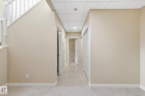 Hallway featuring light beige wall paint, light-toned carpeting, white trim, and white paneled doors - 30 Valleyview Ridge, Fort Saskatchewan, AB - Indoor Photo Showing Other Room