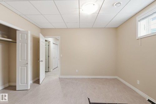 Carpeted room featuring a drop ceiling with recessed lighting, a window with horizontal blinds, a closet with bi-fold doors, and a paneled door entry - 30 Valleyview Ridge, Fort Saskatchewan, AB - Indoor Photo Showing Other Room