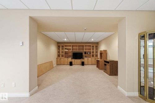 Recessed entertainment area featuring extensive built-in blonde wood cabinetry, integrated shelving, and a drop ceiling with recessed lighting - 30 Valleyview Ridge, Fort Saskatchewan, AB - Indoor