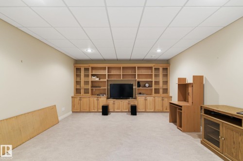 Spacious room featuring extensive built-in cabinetry with glass-front display sections and integrated shelving, recessed lighting, and light-toned carpeting - 30 Valleyview Ridge, Fort Saskatchewan, AB - Indoor