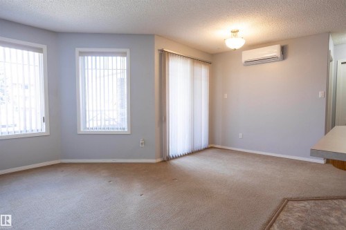 Open living area featuring light gray walls and beige carpeting - 101 2420 108 Street, Edmonton, AB - Indoor Photo Showing Other Room