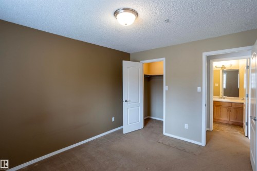 Carpeted bedroom with neutral wall tones and textured ceiling - 101 2420 108 Street, Edmonton, AB - Indoor Photo Showing Other Room