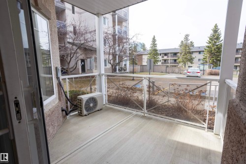 Private concrete balcony featuring glass panel railings with decorative metalwork and a sliding patio door - 101 2420 108 Street, Edmonton, AB - Outdoor With Exterior