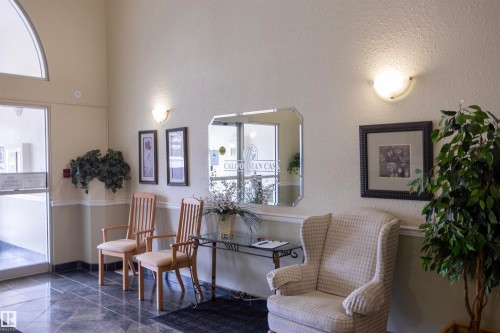 Foyer entry with dark tile flooring, arched transom window, and wall sconce lighting - 101 2420 108 Street, Edmonton, AB - Indoor