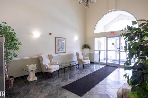 Spacious entrance featuring vaulted ceilings, a large arched transom window, and dark slate tile flooring - 101 2420 108 Street, Edmonton, AB - Indoor Photo Showing Other Room