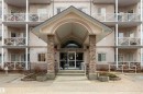 Building entrance featuring a covered arched portico with stone column accents, tiered concrete steps, and a glass double-door entry - 101 2420 108 Street, Edmonton, AB  - Outdoor With Facade 