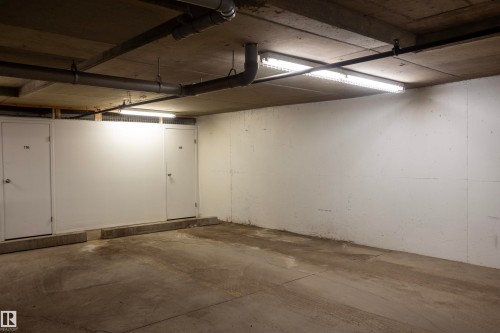 Concrete floor garage space featuring overhead fluorescent lighting and visible utility piping - 101 2420 108 Street, Edmonton, AB - Indoor Photo Showing Garage