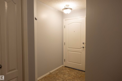 Entryway featuring a paneled door, flush-mount ceiling light fixture, neutral wall paint, and patterned floor tile - 101 2420 108 Street, Edmonton, AB - Indoor Photo Showing Other Room
