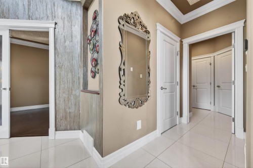 Hallway featuring white square tile flooring, decorative wall paneling, crown molding, and white trim - 1254 Adamson Drive, Edmonton, AB - Indoor