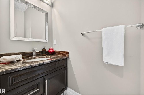 Vanity featuring dark wood cabinetry, a granite countertop with an integrated sink, and a tile backsplash - 1254 Adamson Drive, Edmonton, AB - Indoor Photo Showing Bathroom