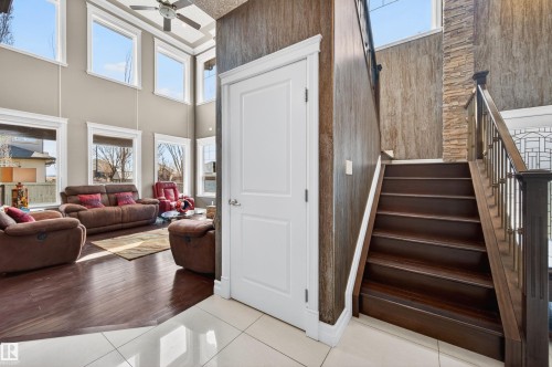 Two-story entryway featuring dark wood-finish stairs with wrought iron balusters, a textured accent wall, and white floor tiles - 1254 Adamson Drive, Edmonton, AB - Indoor