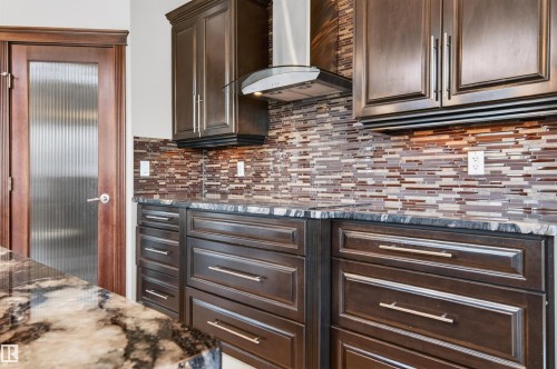 Kitchen featuring dark wood cabinetry with brushed nickel hardware, speckled countertops, and a mosaic tile backsplash - 1254 Adamson Drive, Edmonton, AB - Indoor Photo Showing Other Room