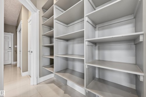 Built-in shelving system with ample storage, featuring light-colored wood-finish shelving, an entryway with light-toned tile flooring, and neutral wall paint - 1254 Adamson Drive, Edmonton, AB - Indoor With Storage