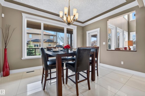 Dining area featuring large windows, white trim, crown molding, a built-in pass-through, and tile flooring - 1254 Adamson Drive, Edmonton, AB - Indoor Photo Showing Dining Room