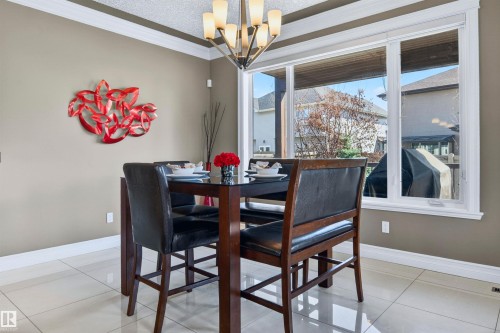 Dining area featuring large windows, crown molding, a contemporary chandelier, neutral wall tones, and tiled flooring - 1254 Adamson Drive, Edmonton, AB - Indoor Photo Showing Dining Room