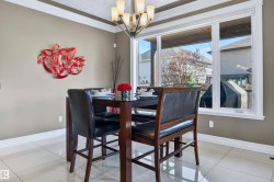 Dining area featuring large windows, crown molding, a contemporary chandelier, neutral wall tones, and tiled flooring - 