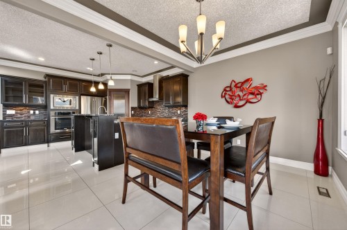 Open-concept dining area featuring a glass-top table, a contemporary chandelier, and large format floor tiles - 1254 Adamson Drive, Edmonton, AB - Indoor Photo Showing Dining Room