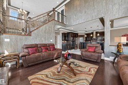 Two-story living area featuring dark wood-finish flooring and a stone-clad fireplace - 