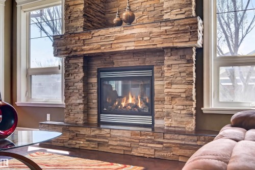 Stacked stone fireplace featuring a gas insert with visible flames - 1254 Adamson Drive, Edmonton, AB - Indoor Photo Showing Living Room With Fireplace
