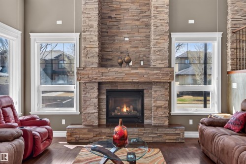 Stacked stone fireplace with a raised hearth, featuring a black firebox and a substantial stone mantel - 1254 Adamson Drive, Edmonton, AB - Indoor Photo Showing Living Room With Fireplace