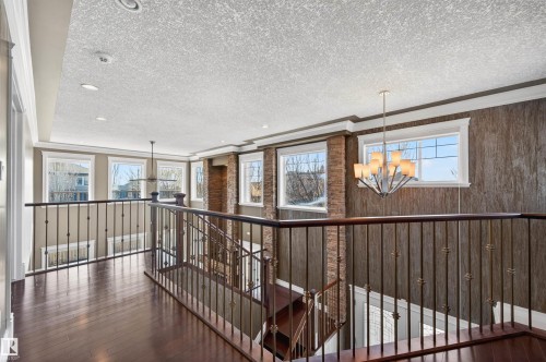 Upper-level landing featuring dark wood-finish flooring, wrought iron railings, multiple windows, recessed lighting, and a contemporary chandelier - 1254 Adamson Drive, Edmonton, AB - Indoor Photo Showing Other Room
