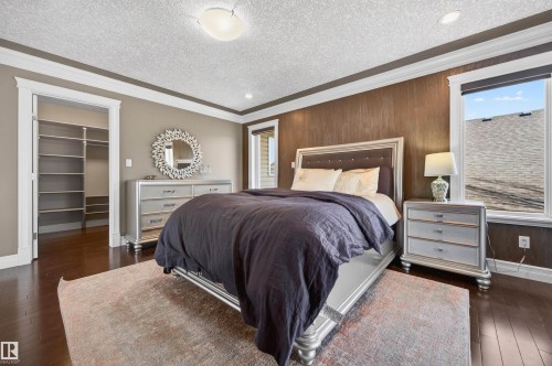 Bedroom featuring wood-finish flooring, accent wall paneling, crown molding, and a built-in closet with shelving - 1254 Adamson Drive, Edmonton, AB - Indoor Photo Showing Bedroom