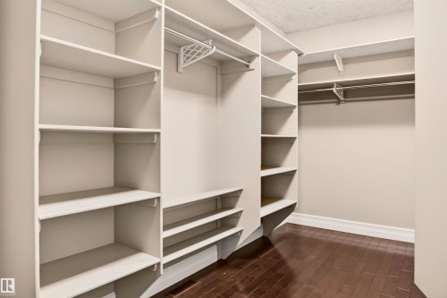 Walk-in closet with dark wood-finish flooring, built-in shelving, and multiple hanging rods - 1254 Adamson Drive, Edmonton, AB - Indoor With Storage