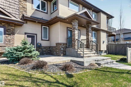 Inviting front entrance featuring stacked stone pillars, concrete steps with wrought iron railings, and a covered porch - 1254 Adamson Drive, Edmonton, AB - Outdoor