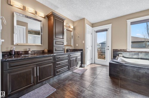 Bathroom featuring a double vanity with dark cabinetry, granite countertops, and individual mirrors - 1254 Adamson Drive, Edmonton, AB - Indoor
