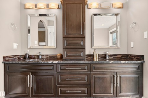 Dual vanity featuring dark wood cabinetry, a dark stone countertop, and mosaic tile backsplash - 1254 Adamson Drive, Edmonton, AB - Indoor